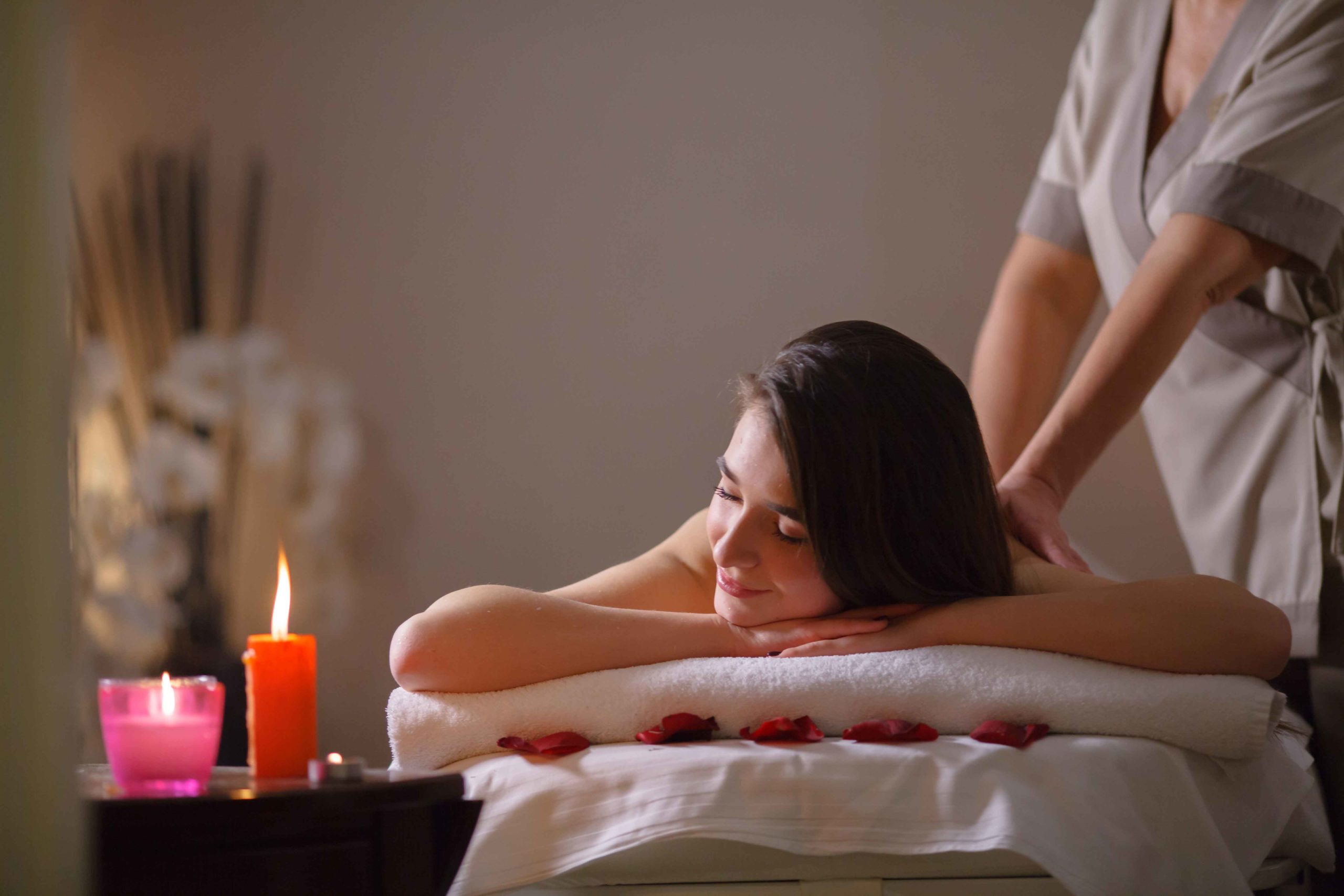 lady enjoying massage by a therapist near scented candles